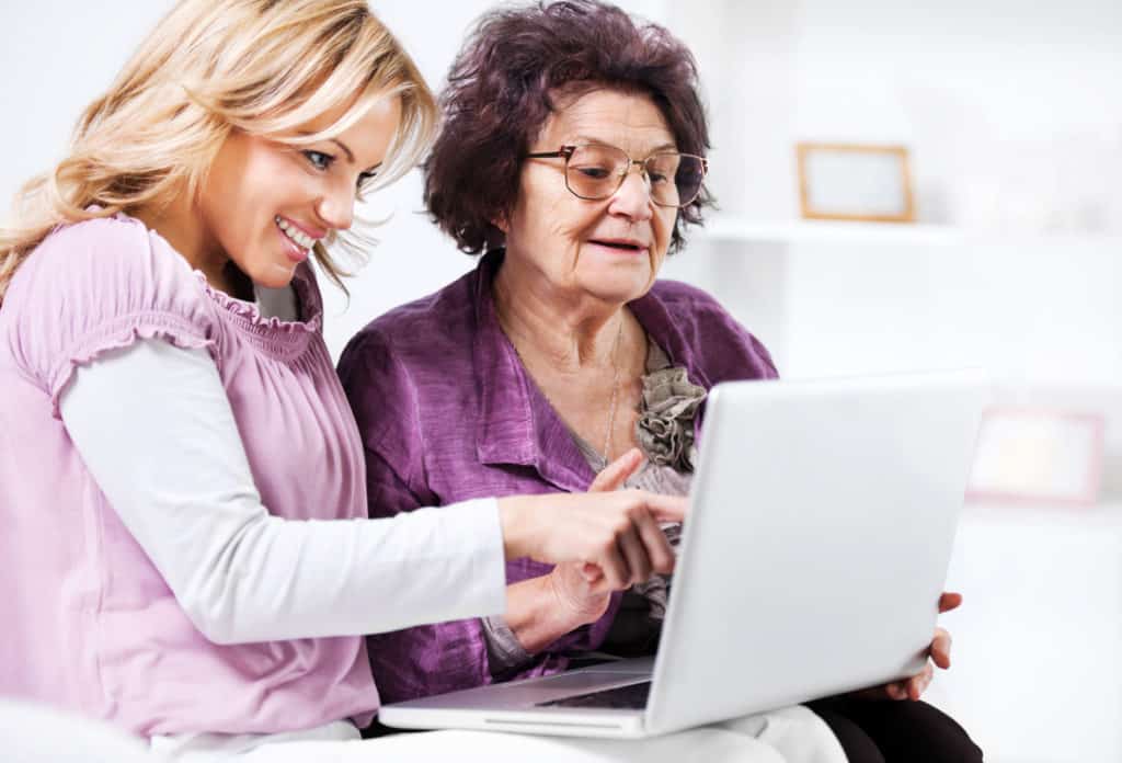 Portrait of a woman showing her elderly mother different assisted living and memory care places online.